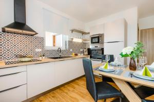 una cucina con mobili bianchi e un tavolo da pranzo di Dům u Mlejna a Petříkov