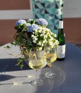 dos copas de vino blanco junto a un jarrón de flores en Haus Valentonio, en Zeltingen-Rachtig