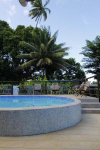 a swimming pool with chairs and a palm tree at Fare Tapu in Uturoa