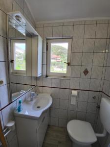 een badkamer met een wastafel, een toilet en een raam bij Apartmani Mira in Rab