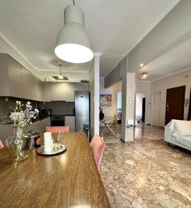cocina y sala de estar con mesa de madera y sillas en Noema Urban Apartment, en Kavala