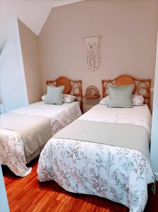 two beds in a room with wooden floors at O balcón do Río in Caldas de Reis