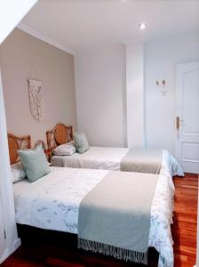 three beds in a room with white walls and wood floors at O balcón do Río in Caldas de Reis