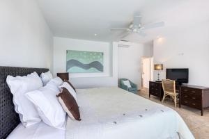 a bedroom with a bed with a ceiling fan and a desk at Villa Lune de Miel in Marigot +18 photos