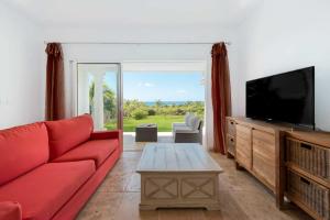 a living room with a red couch and a flat screen tv at Villa Lune de Miel in Marigot