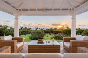 a patio with white furniture and the ocean in the background at Villa Lune de Miel in Marigot