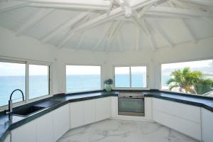 cocina con armarios blancos y vistas al océano en Villa Infinity Blue, en Les Terres Basses
