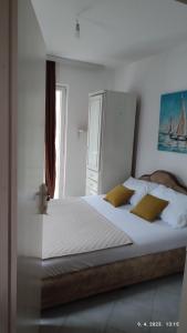 - une chambre avec un grand lit blanc et des oreillers jaunes dans l'établissement Pejovic Guest House, à Sutomore