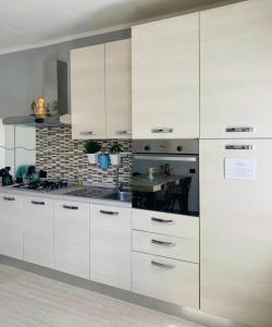 a kitchen with white cabinets and a table in it at Casa Azalea in Colico