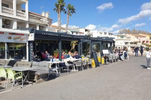 grupa ludzi siedzących przy stolikach przed restauracją w obiekcie Castel du Soleil, Bord de mer, 4 pers w mieście Saint-Cyr-sur-Mer
