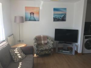 a living room with a couch and a television at Lovely 1-Bed Cottage in Hopeman in Elgin