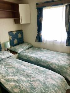 2 camas en una habitación pequeña con ventana en Cornish Caravan on The Lizard Peninsula, Cornwall., en Helston