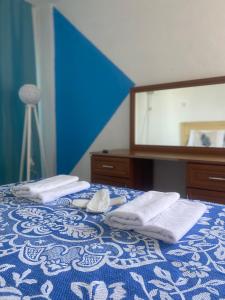 a blue and white bed with towels and a mirror at Deniz Kızı Otel Çeşme in Çeşme