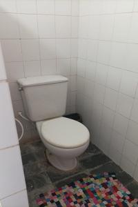 La salle de bains est pourvue de toilettes blanches et d'un tapis coloré. dans l'établissement Chacara c piscina e lazer Sao Lourenco da Mata PE, à São Lourenço da Mata