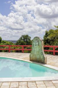 una piscina con una estatua junto a una valla roja en Chacara c piscina e lazer Sao Lourenco da Mata PE, en São Lourenço da Mata