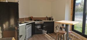 uma cozinha com um fogão e um balcão com uma mesa em Le Pamaro em La Chapelle-dʼAurec