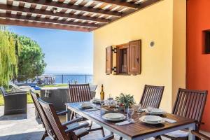 un tavolo in legno con sedie e una sala da pranzo con vista di Villa Calliopé avec vue imprenable, jardin et piscine privée a Glossa