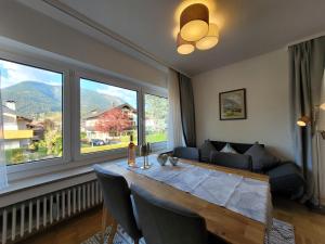 a living room with a table and two large windows at BERG-LOVE in Garmisch-Partenkirchen