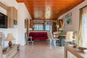 a living room with a red couch and a table at AGGELIKI'S traditional country cottage in Topólia