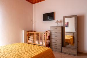a bedroom with a crib and a dresser and a mirror at AGGELIKI'S traditional country cottage in Topólia