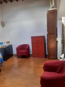 ein Wohnzimmer mit einem roten Stuhl und einer Kommode in der Unterkunft BIRI in Perugia