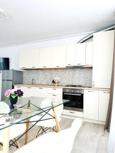 una cucina con armadi bianchi e tavolo in vetro di Miluna Luxury Studios & Apartments a Eforie Nord