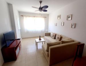 ein Wohnzimmer mit einem Sofa und einem TV in der Unterkunft Disfruta en 1ª línea de playa in Puertito de Güímar