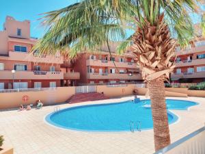 een palmboom en een zwembad voor een gebouw bij Disfruta en 1ª línea de playa in Puertito de Güímar