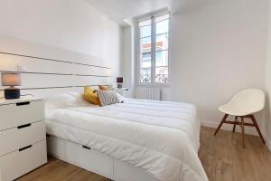 a white bedroom with a white bed and a chair at HENRI CAMILLE REAL ESTATE - Bambou- One bedroom center in Cannes