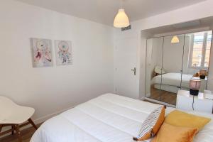 Habitación blanca con cama y espejo en HENRI CAMILLE REAL ESTATE - Bambou- One bedroom center, en Cannes