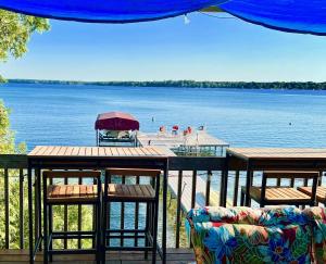 a deck with two tables and chairs and a body of water at The Torch Lake Bed and Breakfast in Central Lake