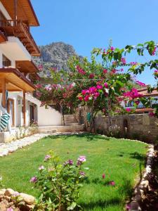 a yard with pink flowers in front of a house at Koparan Apart Hotel in Akyaka