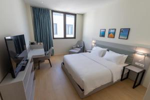 a bedroom with a bed and a desk with a computer at Elements Hotel & Shops Curaçao in Willemstad