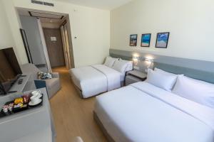 a hotel room with two beds and a television at Elements Hotel & Shops Curaçao in Willemstad