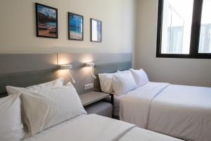 two beds in a hotel room with white sheets at Elements Hotel & Shops Curaçao in Willemstad