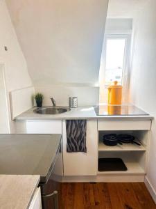 a small white kitchen with a sink and a window at Chaleureux duplex cosy in Caen