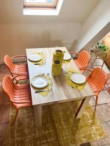 a dining room table with chairs and a table with plates at Chaleureux duplex cosy in Caen