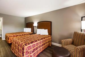 um quarto de hotel com duas camas e uma cadeira em Knights Inn Fayetteville - Fort Bragg em Fayetteville