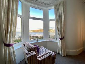 a room with two chairs and two large windows at Dairsie Sea View in Rothesay