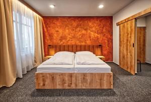 1 dormitorio con cama y pared de color naranja en Restaurace a Penzion Praha, en Dolní Dunajovice