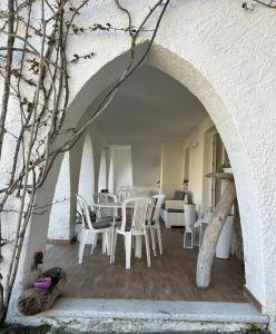 einen Torbogen mit weißen Stühlen und Tischen in einem Zimmer in der Unterkunft Le Bouganville apartment in Santa Teresa Gallura