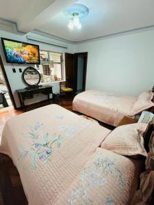 a bedroom with two beds and a flat screen tv at Chaska Hotel in Otavalo