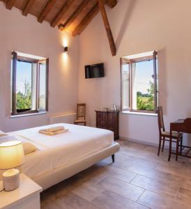 a bedroom with a bed and a desk and two windows at Mahthildis Agriturismo B&B in Vermezzo