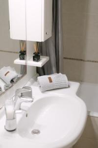 W łazience znajduje się biała umywalka i lustro. w obiekcie The Art Suite w mieście Patras