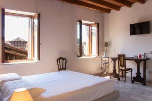 a bedroom with a bed and a table and two windows at Mahthildis Agriturismo B&B in Vermezzo