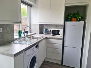 a kitchen with a white refrigerator and a dishwasher at Cozy 2 bedroom house with parking, Aylesbury in Buckinghamshire