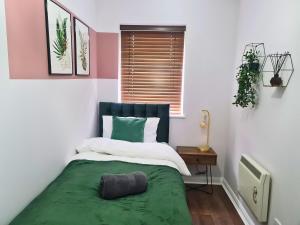 a bedroom with a bed with a green blanket at Cozy 2 bedroom house with parking, Aylesbury in Buckinghamshire