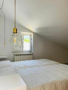 uma cama branca num quarto com uma janela em Casa Lameiro em Lugo
