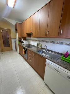 una cocina con armarios de madera y fregadero en Residencial Spiaggia Dorata a 100m de la Playa, en Tarragona