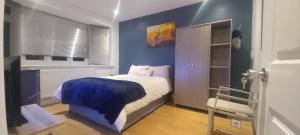 a bedroom with a bed with a blue wall at Feel at Home in Elmers End